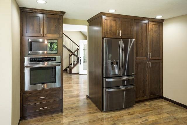 kitchen with appliances with stainless steel finishes, recessed lighting, dark brown cabinetry, and wood finished floors