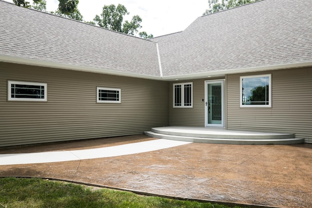 back of property featuring roof with shingles and a patio