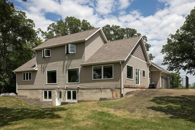 back of house with roof with shingles, a lawn, and a chimney