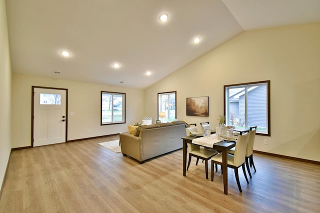 dining area with light wood-type flooring, vaulted ceiling, and baseboards