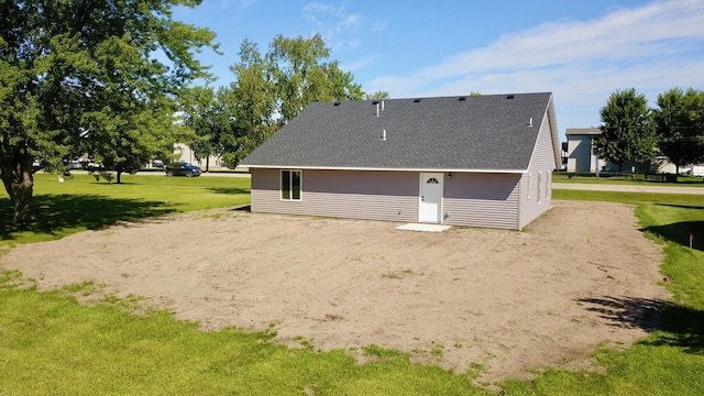 back of house with a shingled roof and a yard