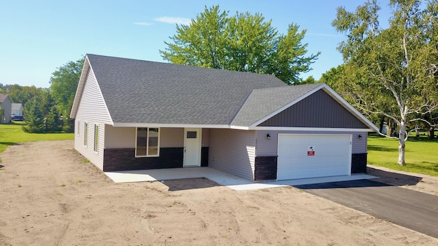 ranch-style house with driveway, stone siding, a shingled roof, and a front yard