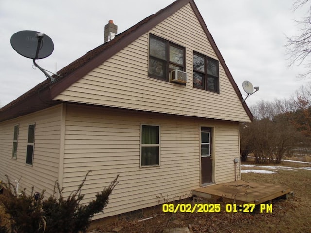 view of side of home featuring cooling unit and a chimney