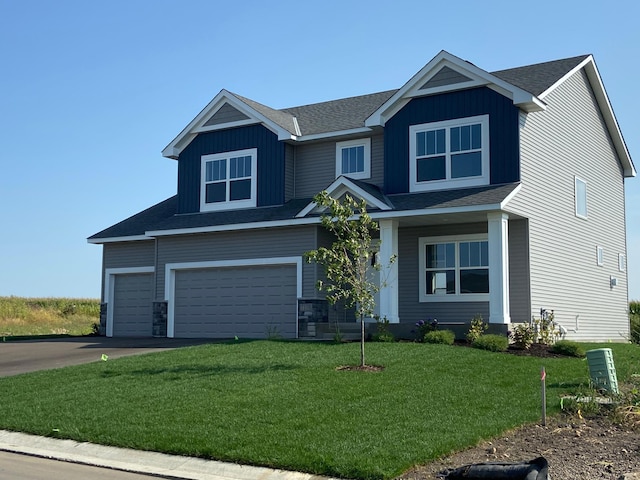 craftsman-style house featuring an attached garage, driveway, board and batten siding, and a front yard