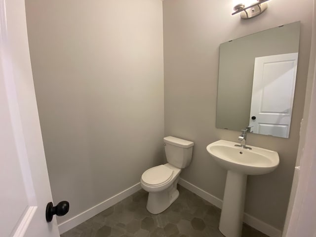 half bath featuring a sink, toilet, and baseboards