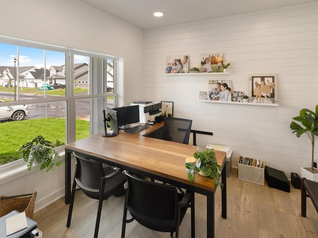 home office featuring light wood finished floors, wooden walls, a residential view, and recessed lighting