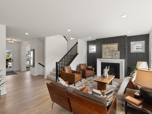 living area with baseboards, a fireplace, recessed lighting, stairs, and light wood-style flooring
