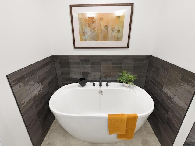 full bathroom with a freestanding tub and tile walls