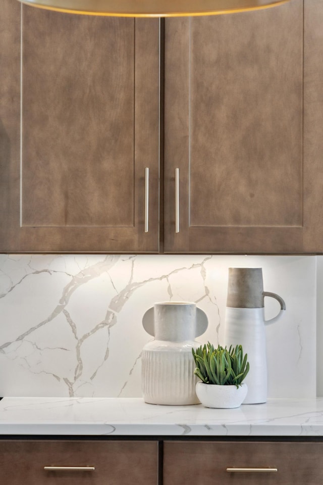 interior details with dark brown cabinets, light stone counters, and decorative backsplash