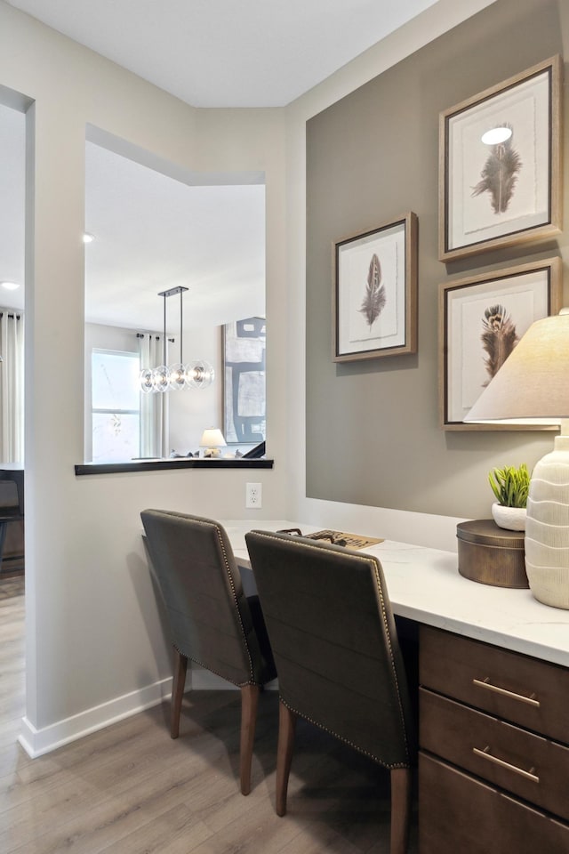 home office with baseboards, light wood finished floors, and built in study area