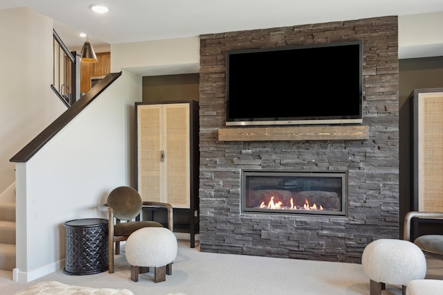 living area with carpet floors, recessed lighting, a stone fireplace, and stairway