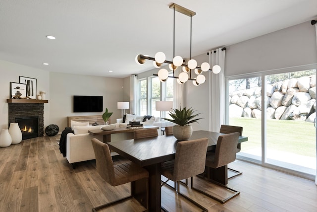 dining space with recessed lighting, a stone fireplace, and hardwood / wood-style floors