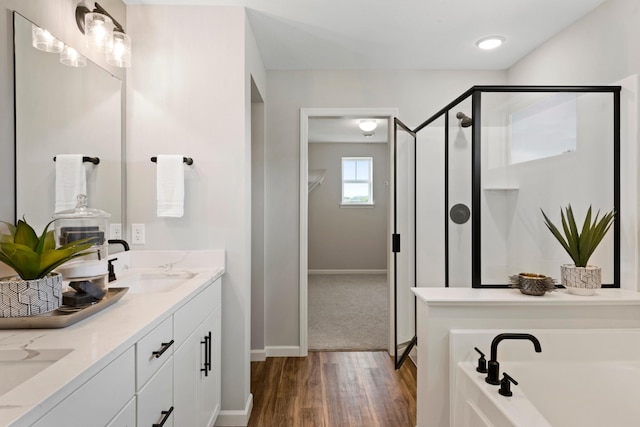 bathroom with wood finished floors, a sink, a spacious closet, a bath, and a stall shower