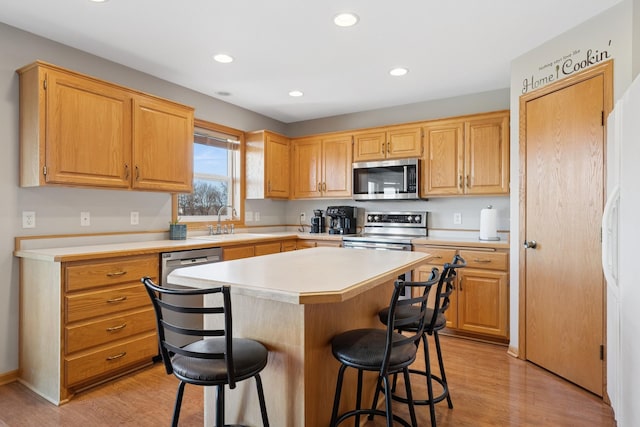 kitchen featuring appliances with stainless steel finishes, a breakfast bar, light countertops, and light wood-style floors