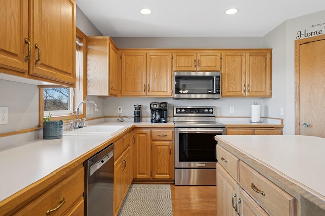 kitchen with a sink, light countertops, recessed lighting, and stainless steel appliances