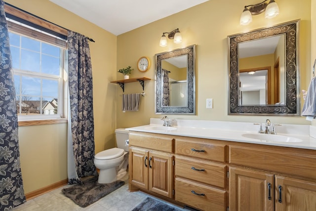 bathroom featuring a sink, baseboards, toilet, and double vanity