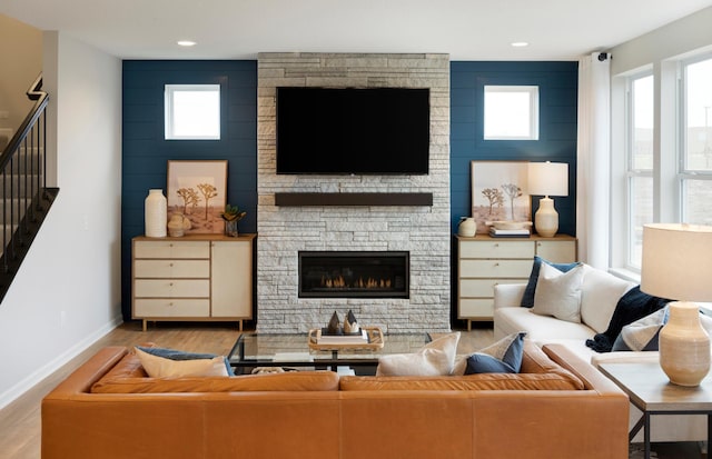 living area featuring baseboards, a fireplace, stairway, and wood finished floors