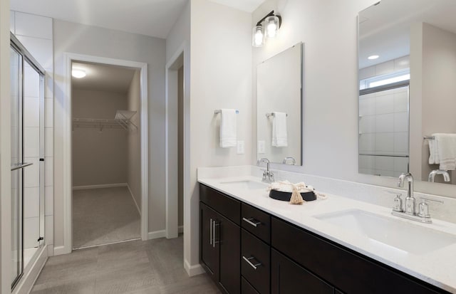 bathroom with double vanity, a shower stall, a walk in closet, and a sink