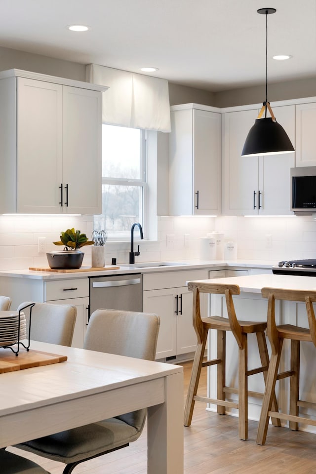 kitchen with appliances with stainless steel finishes, white cabinets, light countertops, and tasteful backsplash