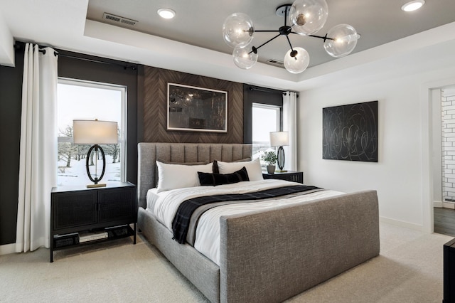 bedroom with light carpet, baseboards, visible vents, and a raised ceiling