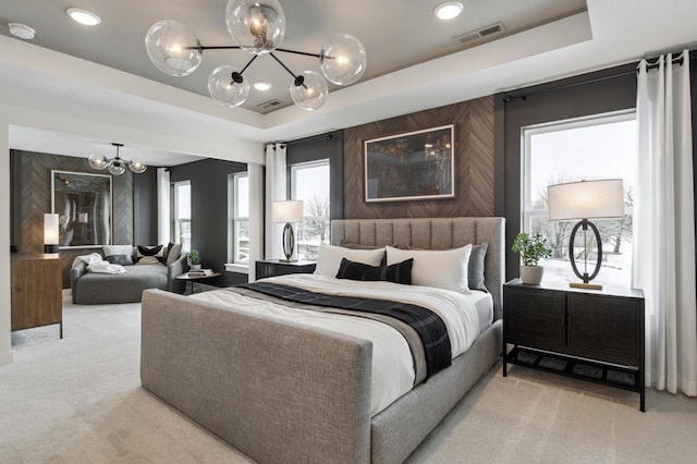 bedroom featuring carpet floors, visible vents, a tray ceiling, and a chandelier