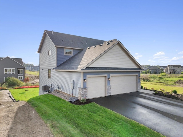 view of side of home featuring aphalt driveway, an attached garage, cooling unit, a yard, and stone siding