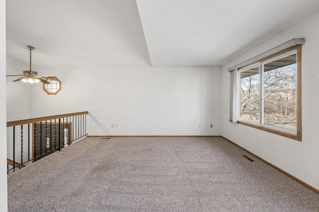 carpeted empty room featuring baseboards, visible vents, and a textured ceiling