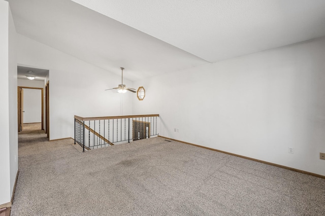 empty room featuring vaulted ceiling, ceiling fan, carpet flooring, and baseboards