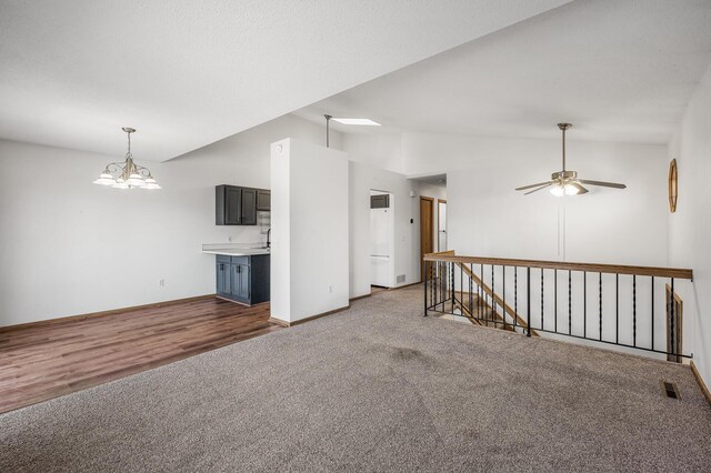 empty room featuring visible vents, baseboards, carpet, vaulted ceiling, and ceiling fan with notable chandelier