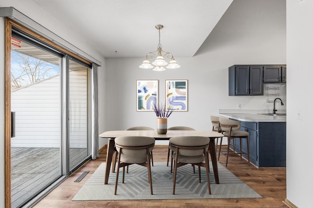 dining area with light wood-style floors, a chandelier, visible vents, and baseboards