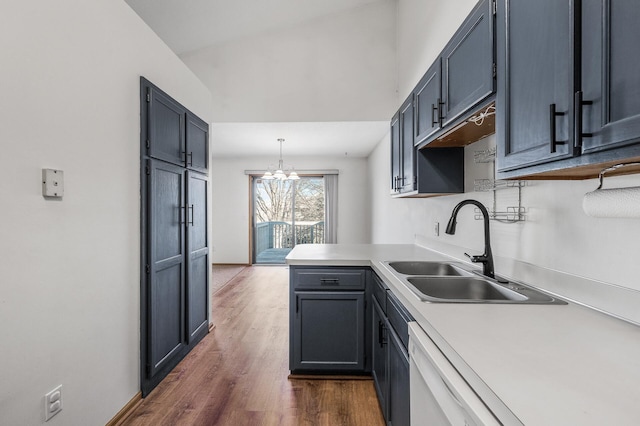 kitchen with pendant lighting, dark wood finished floors, light countertops, a sink, and a peninsula