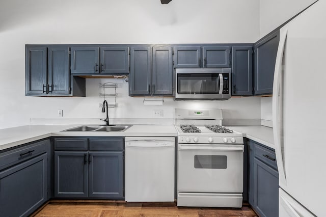 kitchen with white appliances, light countertops, a sink, and wood finished floors