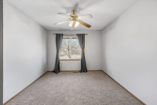 spare room with carpet floors, a textured ceiling, baseboards, and a ceiling fan