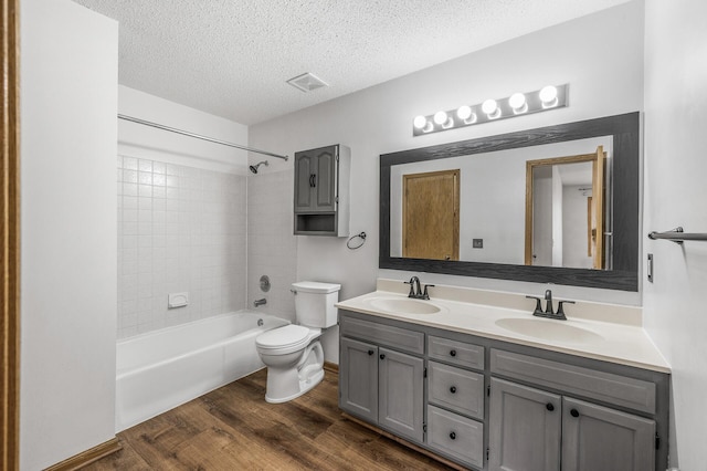 bathroom with toilet, wood finished floors, a sink, and visible vents