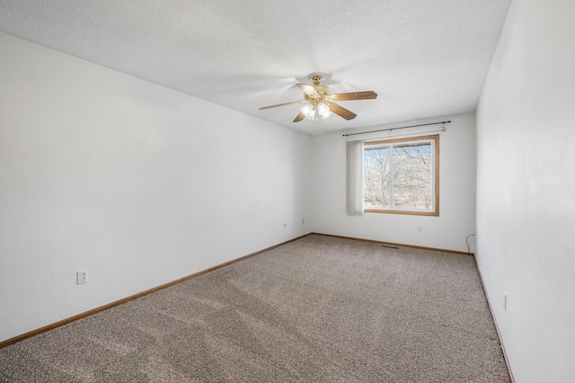 carpeted spare room featuring a textured ceiling, visible vents, a ceiling fan, and baseboards