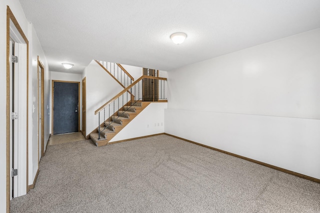 interior space featuring a textured ceiling, stairs, baseboards, and carpet flooring