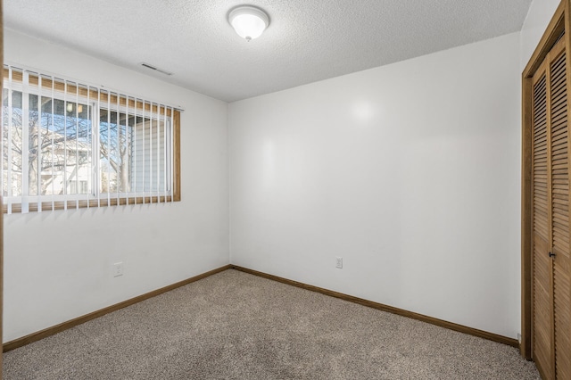 unfurnished bedroom with carpet, a closet, visible vents, a textured ceiling, and baseboards