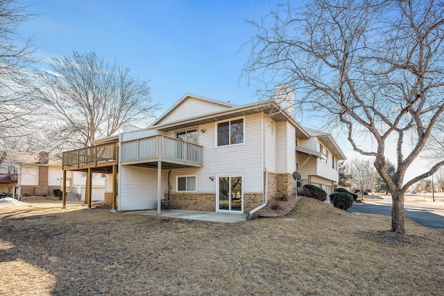 back of property featuring a chimney, a deck, a patio, and brick siding