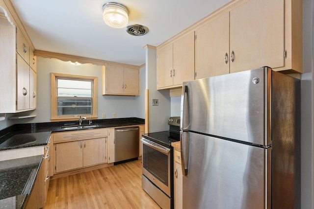 kitchen featuring visible vents, appliances with stainless steel finishes, light wood-style floors, a sink, and dark stone counters