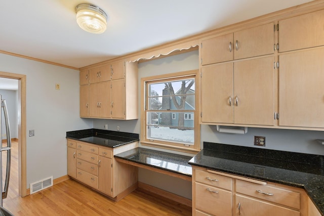 kitchen featuring crown molding, light wood finished floors, visible vents, dark stone counters, and baseboards