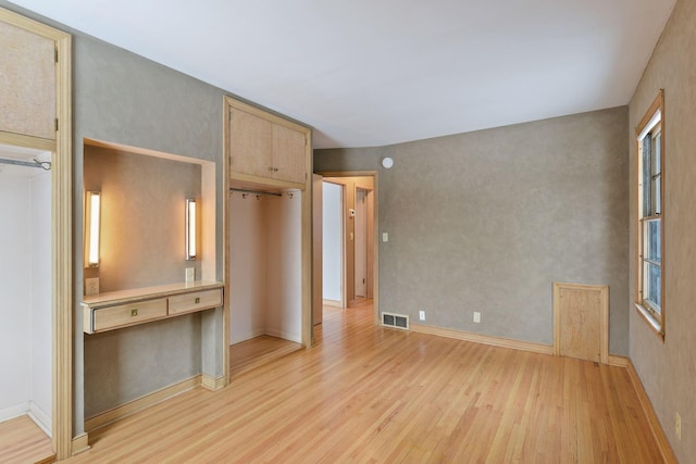 unfurnished room featuring light wood finished floors, visible vents, and baseboards