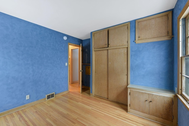 unfurnished bedroom featuring light wood finished floors, a closet, and visible vents