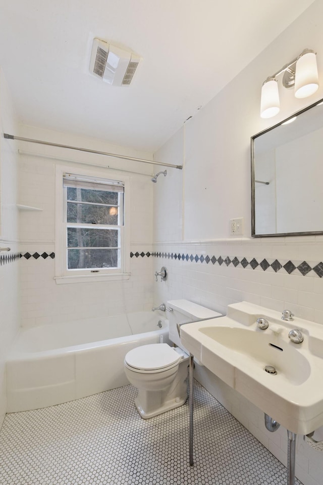 bathroom with tile walls, shower / bath combination, visible vents, toilet, and tile patterned floors