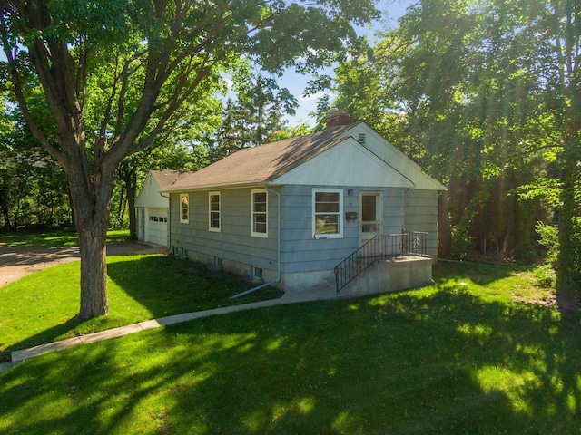 view of side of property featuring an attached garage, driveway, a lawn, and a chimney