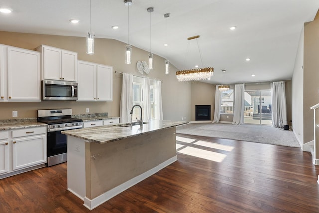 kitchen featuring dark wood-style floors, light stone countertops, appliances with stainless steel finishes, and a sink