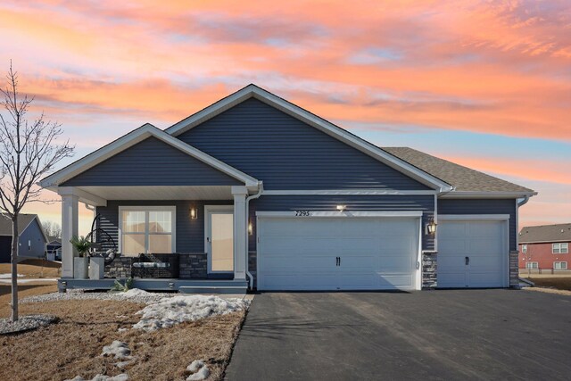 7295 Parson Ct NE, Otsego, MN 55330 - view of front of house featuring stone siding, covered porch, driveway, and a garage