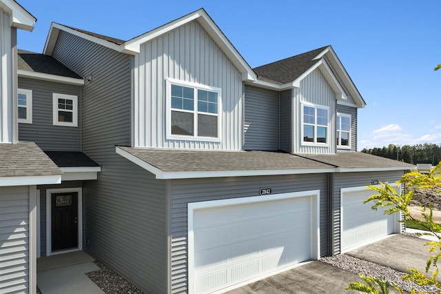 view of front facade featuring an attached garage, board and batten siding, and roof with shingles