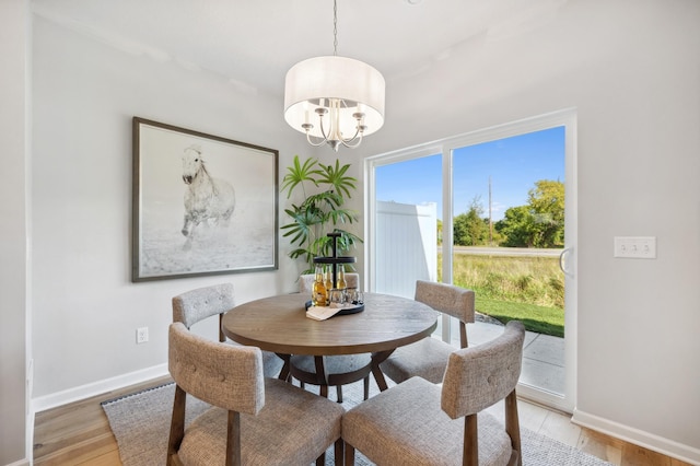 dining space featuring an inviting chandelier, light wood-style flooring, and baseboards