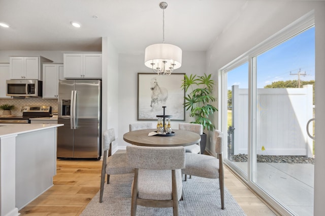 dining area with light wood-type flooring, recessed lighting, and an inviting chandelier