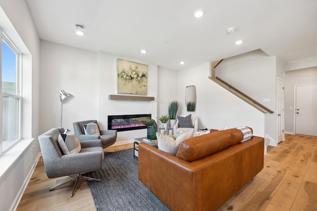 living room with light wood-type flooring, a glass covered fireplace, and recessed lighting